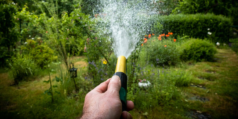 Eine Hand mit Gartenschlauch