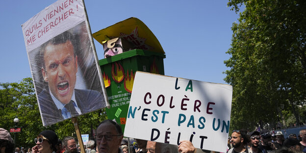 Ein Demonstrant trägt eine Mülltonne mit einem Bildnis, das den französischen Präsidenten Macron darstellt