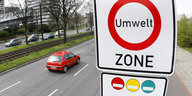 Schild einer Umweltzone an einer Straße, Im Hintergrund fährt ein rotes Auto vorbei