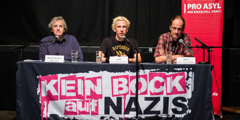 Pressekonferenz von Pro Asyl. Drei Männer sitzen an einem Tisch.