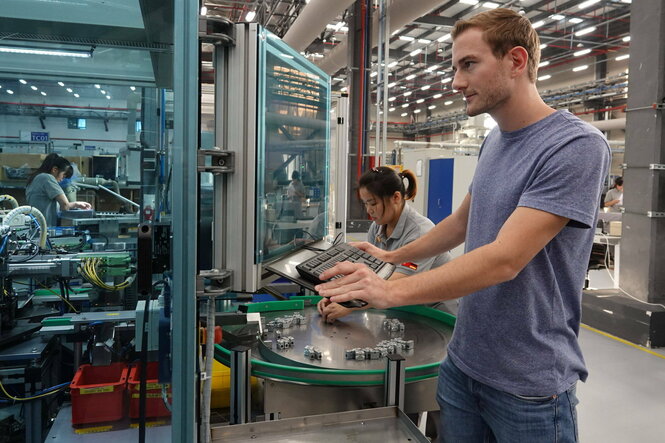 Ein junger Mann und eine Chinesin arbeiten in einer Fabrik