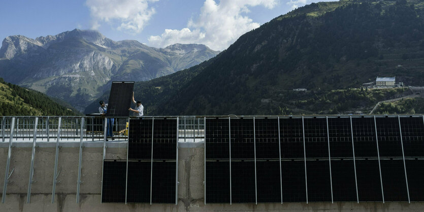 Arbeiter montieren Solarpanels an einem Stausee entlang