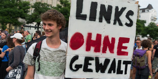 Ein Demonstrant hält ein Schild mit der Aufschrift "Links ohne Gewalt" hoch