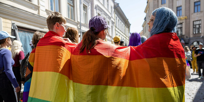 Menschen gehüllt in eine Regenbogenfahne