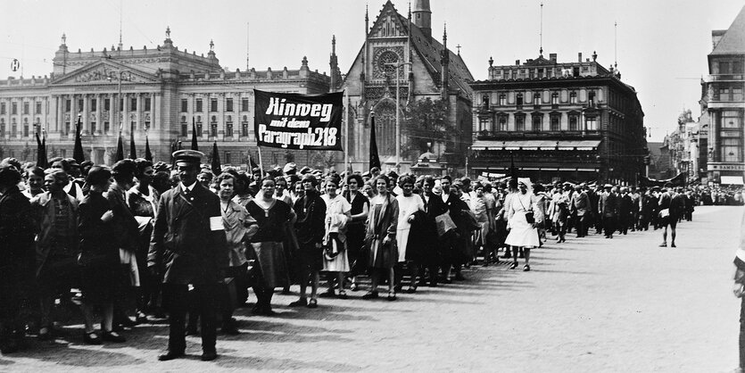 Menschen demonstrieren mit einem Transparent, auf dem ist zu lesen "Hinweg mit dem Paragraphen 218", historische Aufnahme