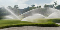 Wasserfontänen bewässern einen Golfplatz