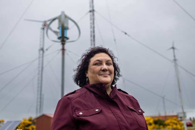 Eine Frau mit roter Jacke steht vor Geräten, die in den Himmel ragen