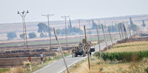 Militärfahrzeuge auf einer einsamen Straße mit Feldern links und rechts