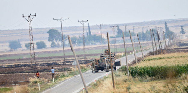Militärfahrzeuge auf einer einsamen Straße mit Feldern links und rechts