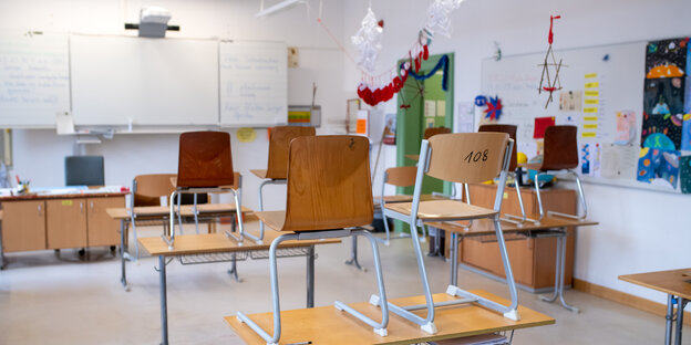 Ein Klassenzimmer mit zwei Bänken und Stühlen die darauf gestellt sind