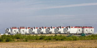 Bauteile von Windanlagen liegen auf einem Feld