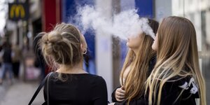 Drei junge Frauen rauchen auf der Straße