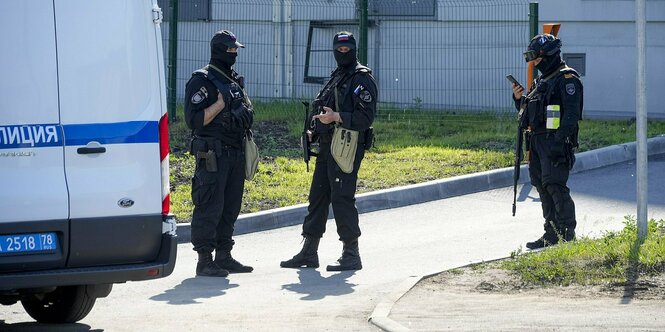 Vermummte russische Polizisten stehen vor dem "PMC Wagner-Zentrum" in Sankt Petersburg