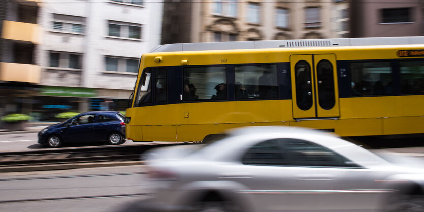 Eine Straßenbahn fährt hinter Autos vorbei durch die Stadt