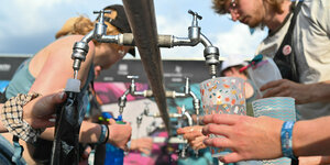 Mehrere Personen zapfen Trinkwasser bei einem Musikfestival