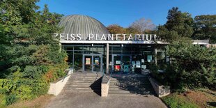 Das Planetarium am Insulaner schaut mit seinem Ausgangsbereich aus den bäumen hervor. Dahinter ist die Kuppel zu sehen.