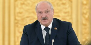 Alexander Lukaschenko sitzt am 6. April 2023 vor einer prunkvollen Wand und spricht in ein Mikrofon