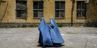 Zwei in blaue Burkas gehüllte Frauen vor einem Haus