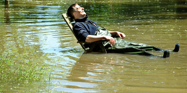 Ein Mann sitzt in einem Liegestuhl bei Hochwasser