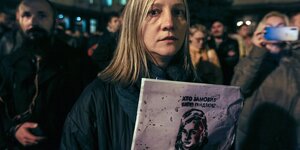 Eine Frau hält ein Plakat mit dem Stencil des Gesichts von Kateryna Handsjuk