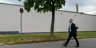 Ein Mann in schwarzem Anzug geht eine Strasse entlang
