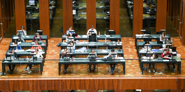 Menschen sitzen an Arbeitsplätzen in der Universitätsbibliothek der Humboldt-Universität