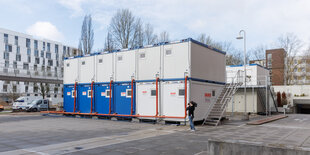 Duschcontainer stehen in einem Hof der leerstehende Postbank-Zentrale in der City Nord.