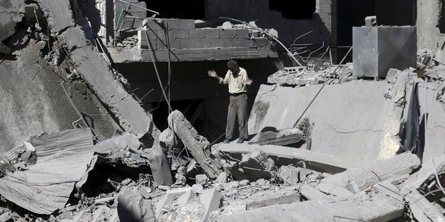 Ein Mann steht in den Trümmern eines Wohnhauses