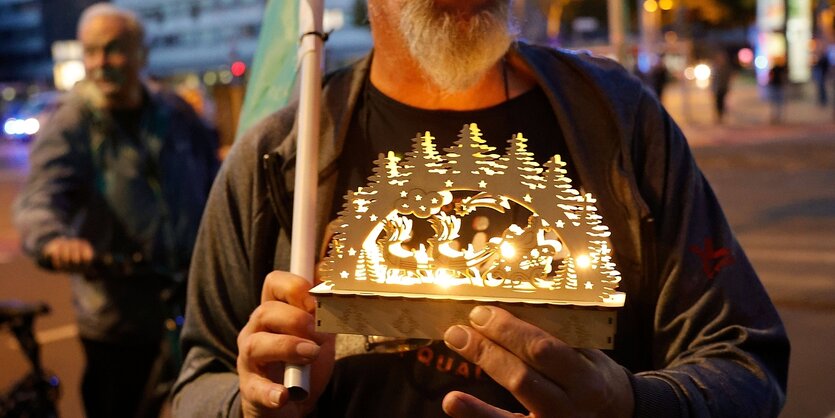 Ein Demonstrant hält einen Schwibbogen in die Kamera