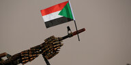 Sudanesische Nationalflagge angesteckt an ein mit Mution vollgeladenes Maschinengewehr