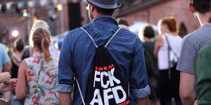 Ein mann trägt einen Rucksack mit der Aufschrift FCK AFD