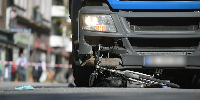 Ein verbogenes Fahrrad liegt auf der Straße unter einem blauen Lkw