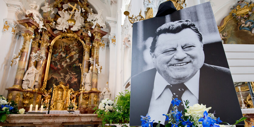 In einer Kirche. Ein Altar, daneben ein Bild von Franz Josef Strauß.