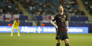 Ein Fußballer steht im Stadion, die Hände an den Hüften