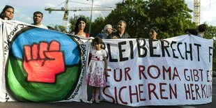 Ein Mädchen steht während einer Roma Demonstration zwischen Transparenten