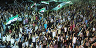 Hunderte recken die Arme und tragen die Fahne der Revolutionären Syrer