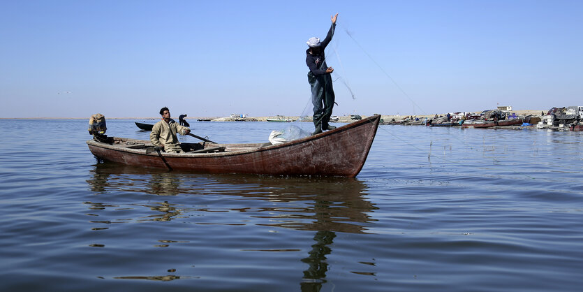 Kleines Fischerboot, ein Fischer wirft das Netz aus