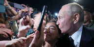Wladimir Putin küsst in einer Menge ein Mädchen auf die Schläfe