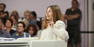 Valeria Gordeev sitzt in weißer Bluse in einem weißen Sessel vor Zuschauer:innen