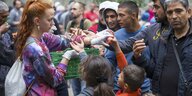 Eine Frau verteilt Äpfel an Flüchtlinge