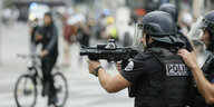 Ein französischer Polizist mit Waffe zielt auf auf jemanden, während eines Protest