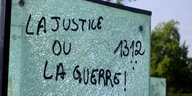 Auf einer zerbrochenen Scheibe steht "Gerechtigkeit oder Krieg"
