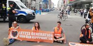 Aktivist:innen sitzen mit einem Transparent auf der Friedrichstraße