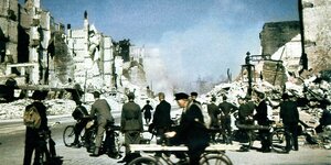 Männer auf Fahrrädern und in Uniform begutachten das ausgebombte Hamburg, blauer Himmel im Juli 1943