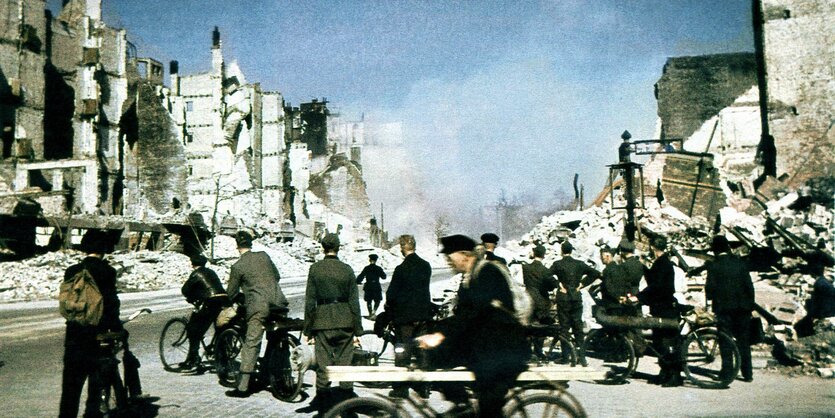 Männer auf Fahrrädern und in Uniform begutachten das ausgebombte Hamburg, blauer Himmel im Juli 1943