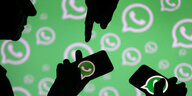Mehrere Menschen halten ein Smartphone vor einem Hintergrund mit dem WhatsApp-Logo