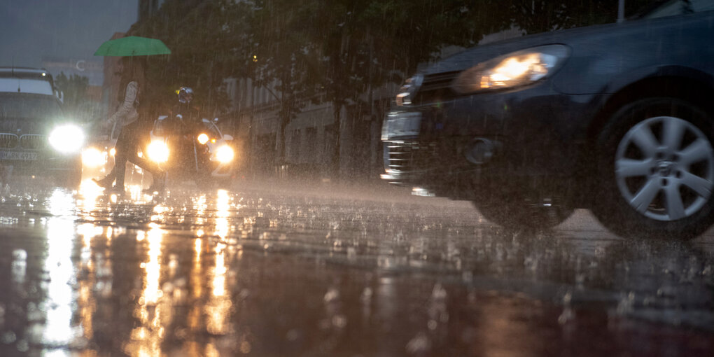 Ein Mann geht im Regen über die Straße.