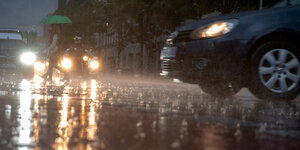 Ein Mann geht im Regen über die Straße.