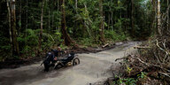 Ein Polizist schiebt ein Motorrad durch einen überfluteten Waldweg im Amazonas in Brasilien
