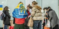 Eine Frau mit ukrainischer Flagge um die Schultern wird gemeinsam mit einer anderen Frau beraten